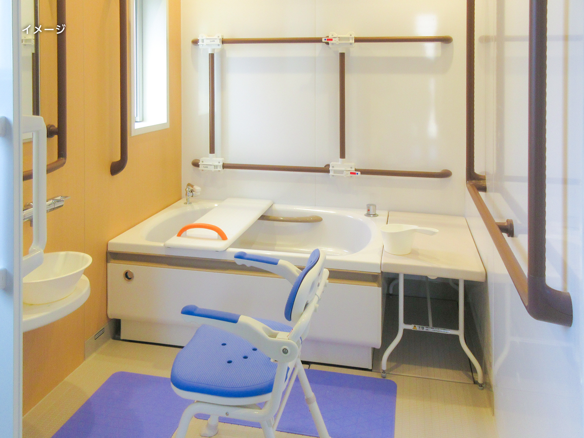 介護用浴室。白い浴槽と入浴補助具、手すりが備えられている。