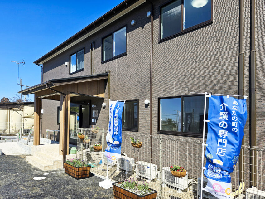 介護施設の玄関・車寄せエリア。青いのれんと看板が見える